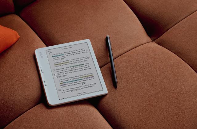 Product lifestyle photo of the Kobo Libra Colour ereader. It sits on a couch with color highlighting and annotations. A stylus sits to its right.