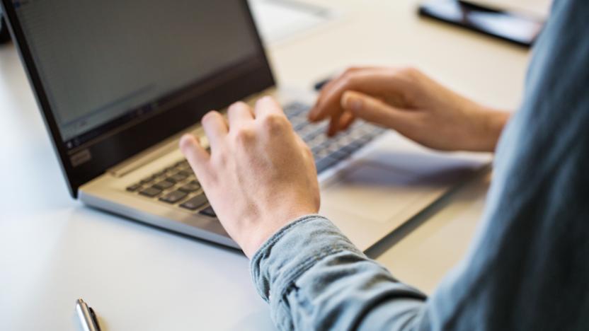 Close up of female hand using laptop on office table. Cropped shot of businesswoman working on laptop.