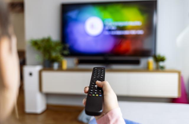 Hand with remote control in front of the tv