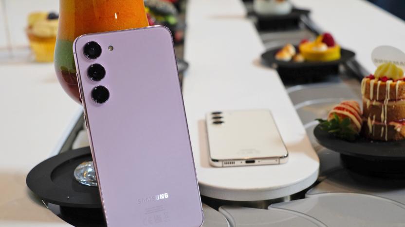 A Samsung Galaxy S23+ smartphone is propped up in the middle of a conveyor belt with food.