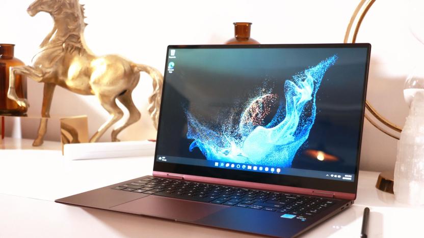 A burgundy Galaxy Book 2 Pro 360 sitting on a white desk with an S Pen to its right.