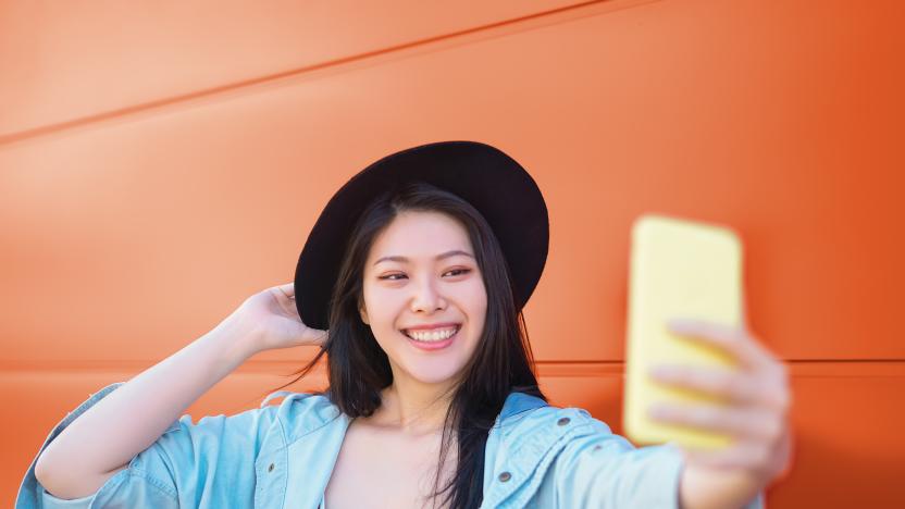 Happy Asian girl taking selfie with mobile smart phone outdoor - Trendy influencer having fun with new trends social networks apps - Millennial generation lifestyle people addicted technology