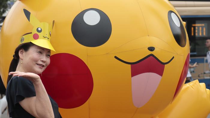 A woman poses with a balloon of Pokemon character Pikachu at Minatomirai shopping district in Yokohama, near Tokyo, Monday, Aug. 14, 2017. (AP Photo/Shizuo Kambayashi)