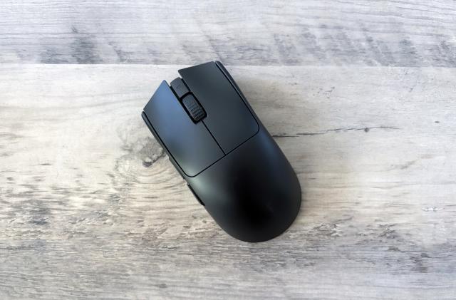 A black Razer Viper V3 Pro gaming mouse rests slightly angled on top of a light brown wooden table.