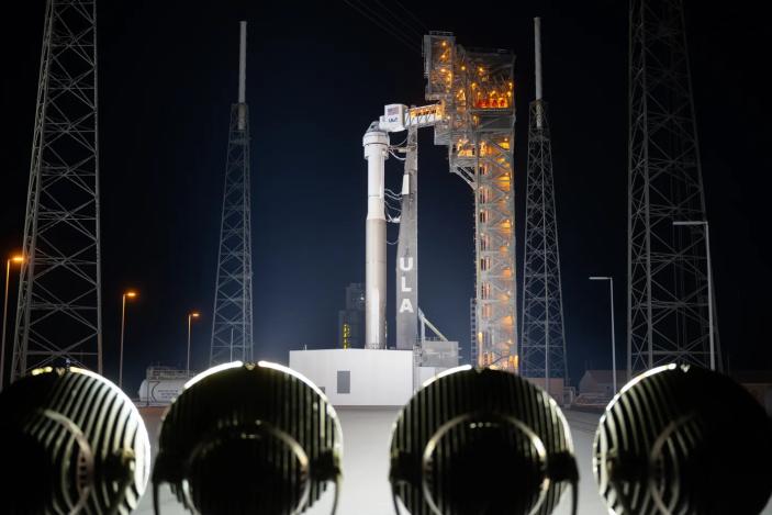 Starliner sitting atop a ULA Atlas V rocket on the launch pad at night