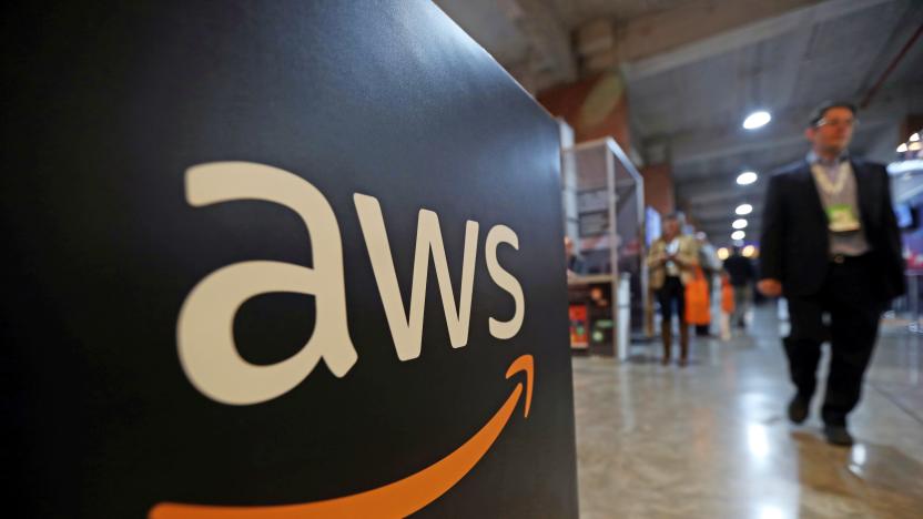 A man walks past an Amazon AWS sign with logo.