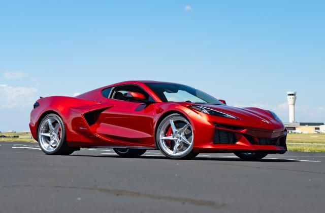 A burgundy Chevrolet Corvette E-Ray sits on what appears to be an airport runway.
