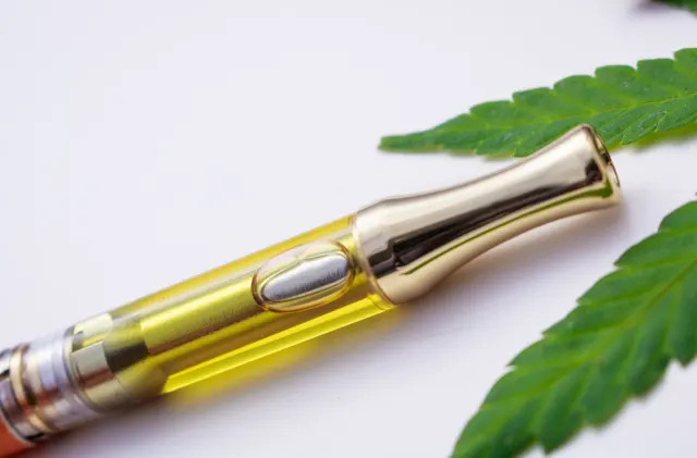 Full gram cartridge with cannabis oil and terpenes inside. With weed leaf on white background. An alternative method of smoking medical marijuana.