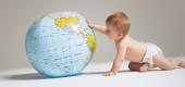 A baby pushes a giant globe. (Getty Images)