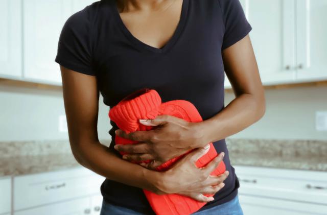 Woman Suffering from Stomach Pain Uses Hot Water Bottle