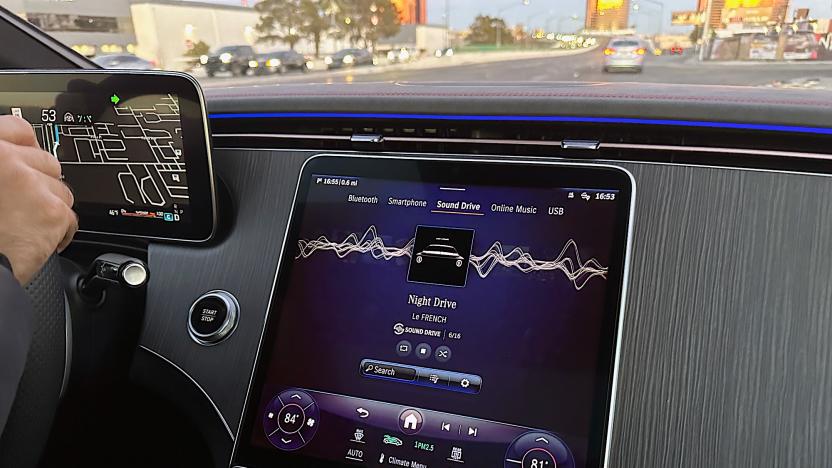 Image of the media unit at the front of a Mercedes AMG showing MBUX SOUND DRIVE, a new immersive audio system coming mid-2024. The image is of a car dashboard with a street scene in the upper third.