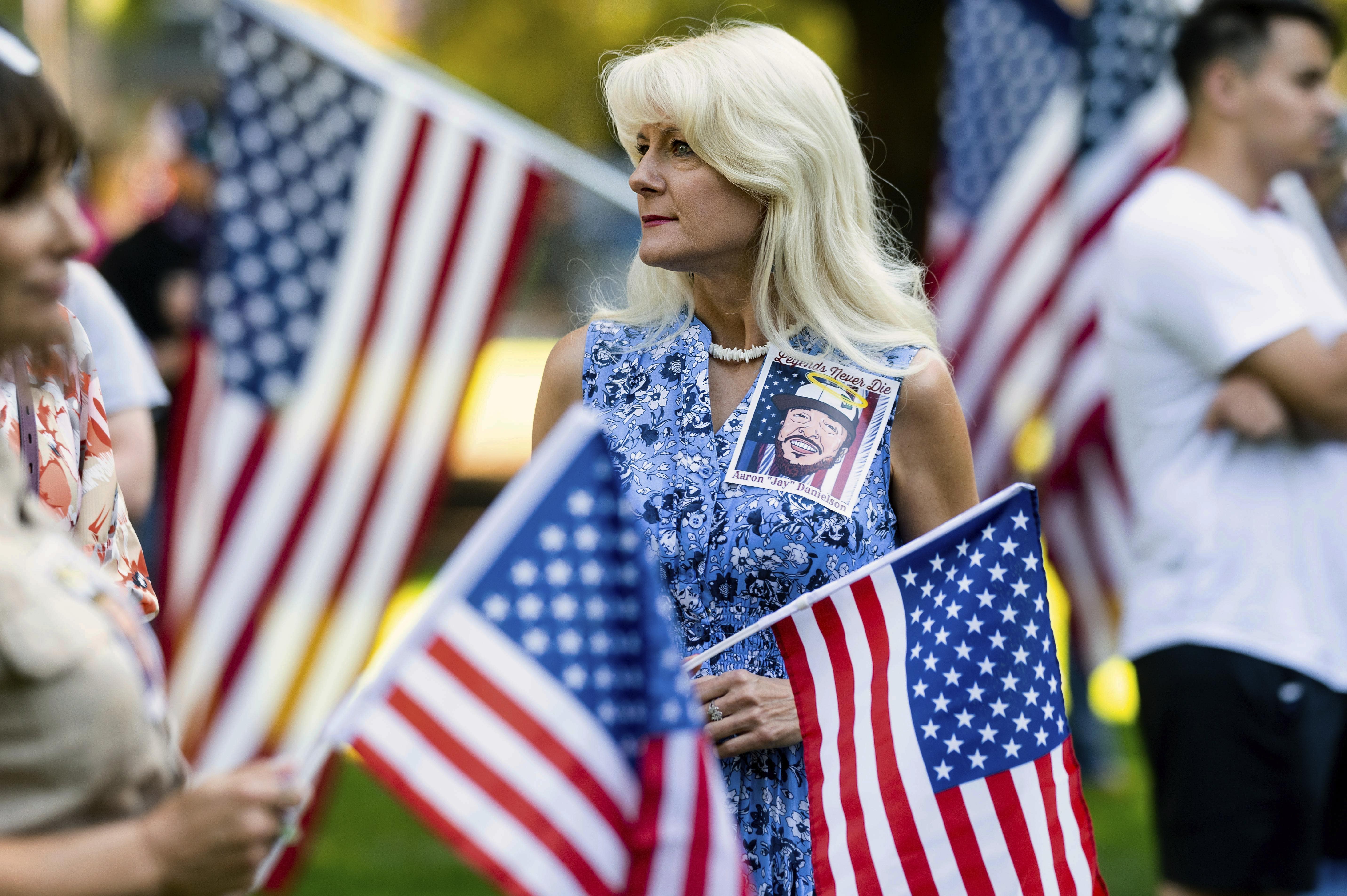 A woman wears an image of Aaron J. Danielson during a memorial for him on Saturday, Sept. 5, 2020, in Vancouver, Wash. Danielson, a supporter of the conservative group Patriot Prayer, was fatally shot in August as supporters of President Donald Trump and Black Lives Matter protesters clashed in Portland, Ore. (AP Photo/Noah Berger)