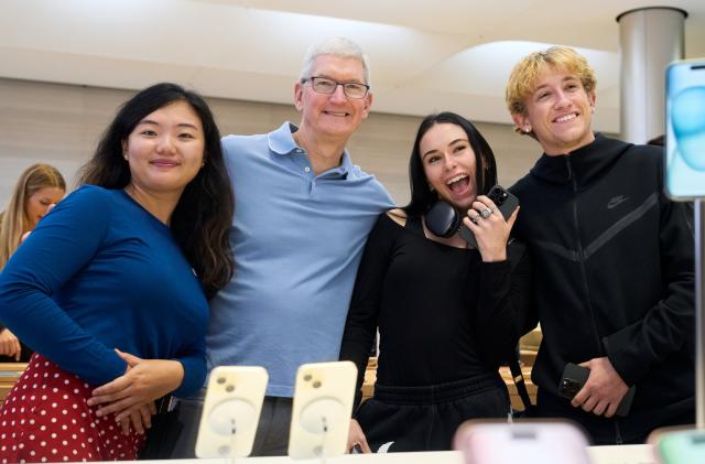 Four people posing behind a table with iPhone displays.