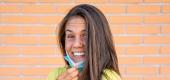 Person pulls mask down her chin. (Getty Images)