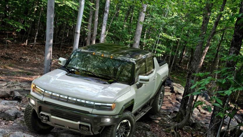 The Hummer EV navigating uneven rocky terrain in a forest.