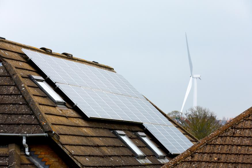 A solar energy panel is pictured on the roof of a house with a wind turbine seen in the background, in Burton Latimer, Britain, March 30, 2022. 