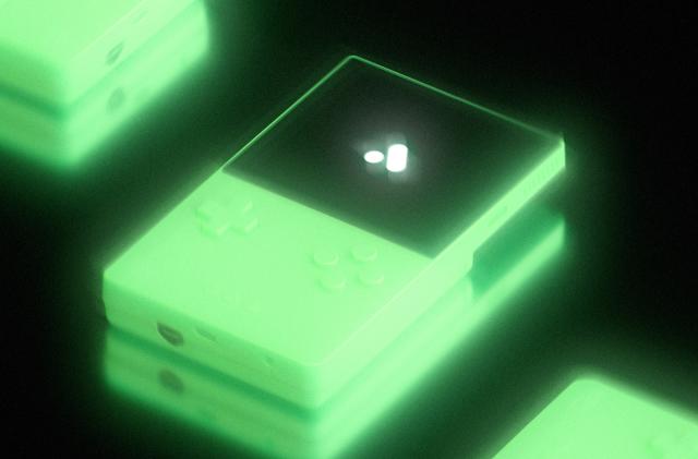 A glowing handheld console against a black backdrop.