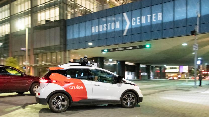 A white car with orange Cruise branding in front of the Houston Center