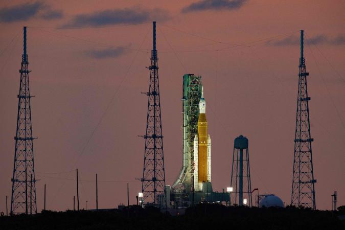 TOPSHOT - The Artemis I unmanned lunar rocket sits on launch pad 39B at NASA's Kennedy Space Center in Cape Canaveral, Florida, on September 25, 2022, just hours before it begins its rollback to the Vehicle Assembly Building (VAB). - NASA's Artemis 1 rocket -- waiting to blast off on a delayed mission to the Moon -- will be rolled back into its storage hangar Monday night, the space agency said, as Florida braces for Hurricane Ian. (Photo by Jim WATSON / AFP) (Photo by JIM WATSON/AFP via Getty Images)