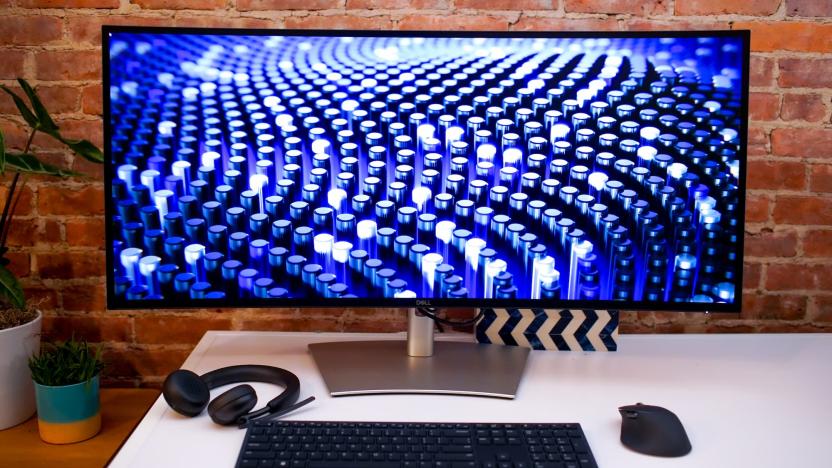 Dell's UltraSharp 40 Curved Thunderbolt Hub Monitor on a desk with a keyboard, mouse and headphones placed in front.
