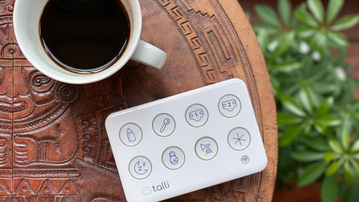 An overhead view of the Talli Baby tracker and a cup of coffee on a small round table.