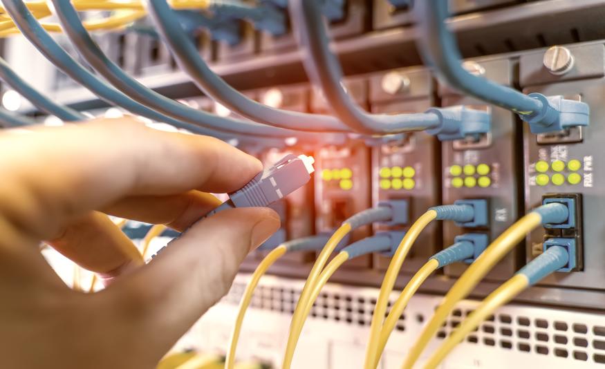 hand with fiber network cables connected to servers in a datacenter