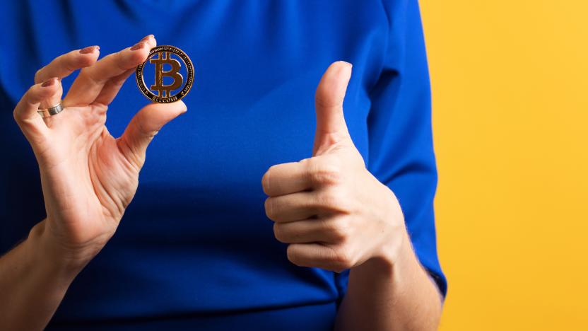 Faceless girl holds golden physical bitcoin and shows Okay sign, thumbs up, ok gesture. Female Hand with Cryptocurrency Coin on Blue Yellow Background. Digital Currencies, Cryptocurrencies, Blockchain