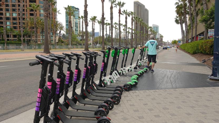 A row of new electric dockless scooters from Lyft is parked by the side of a road in downtown San Diego, ready to be rented. Lyft is one of the latest companies to join the dockless market. In the background, there are also scooters from Limebike.