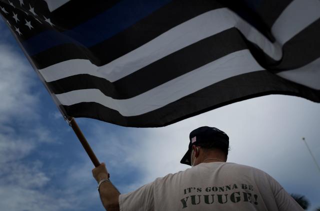 A supporter of US President Donald Trump waves a "Blue Lives Matter" flag as he attends a rally outside the "Latinos for Trump Roundtable" event in Doral, Florida, on September 25, 2020. (Photo by Marco BELLO / AFP) (Photo by MARCO BELLO/AFP via Getty Images)