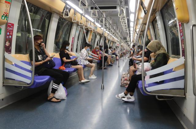 SINGAPORE - JUNE 02:  Commuters wearing protective mask ride the train on June 2, 2020 in Singapore. The authority decided to remove all safe distancing stickers and markers from trains and buses as they deemed it is too challenging for commuters to keep their social distance. Today, Singapore embarks on phase one of a three phase approach against the coronavirus (COVID-19) pandemic as it begins to ease the partial lockdown measures by allowing the safe re-opening of economic activities which do not pose high risk of transmission. This include the resumption of selected health services, re-opening of schools with school children attending schools on rotational basis, manufacturing and production facilities, construction sites that adhere to safety measures, finance and information services that do not require interactions and places of worship, amongst others. Retail outlets, social and entertainment activities will remain closed and dining in at food and beverage outlets will still be disallowed. The government will further ease restriction by the middle of June if the infection rate within the community remains low over the next two weeks.(Photo by Suhaimi Abdullah/Getty Images)