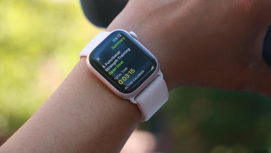 The Apple Watch Series 9 on a person's wrist, with the hand holding a black water bottle in the background. The screen shows the summary of a Functional Strength Training workout.
