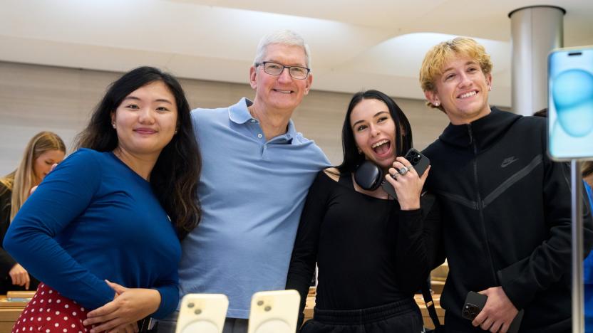 Four people posing behind a table with iPhone displays.