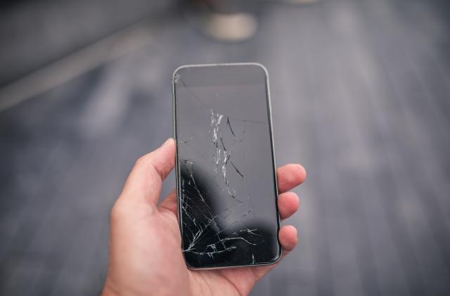 Man holding a broken smart phone in his hand, part of.