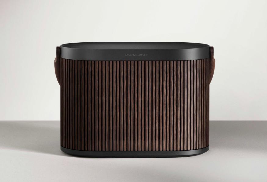 The Bang & Olufsen Beosound A5 speaker, which looks like a combination of an air filter and lunch pail, sits on a grey surface in front of a white wall.