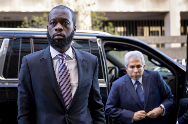 Prakazrel “Pras” Michel, left, a member of the 1990s hip-hop group the Fugees, accompanied by defense lawyer David Kenner, right, arrives at federal court for his trial in an alleged campaign finance conspiracy, Thursday, March 30, 2023, in Washington. (AP Photo/Andrew Harnik)