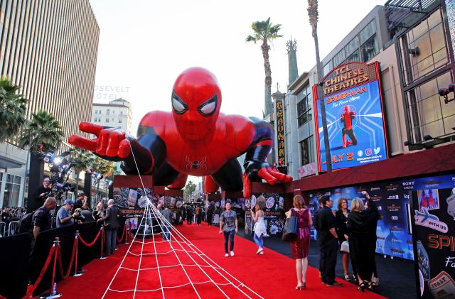 An inflatable spider-man hovers over the red carpet of a film premiere.