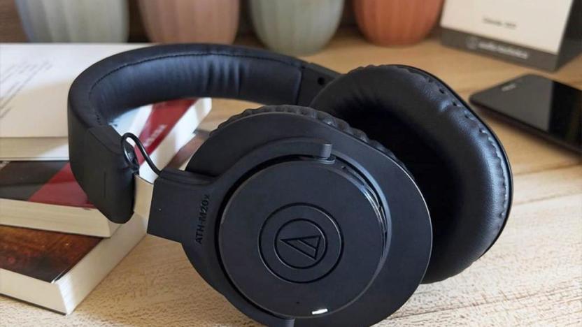 The Audio-Technica ATH-M20xBT headphones sit on a desktop amongst books, small planters and a phone.