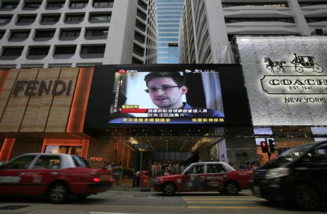 A TV screen shows a news report of Edward Snowden, a former CIA employee who leaked top-secret documents about sweeping U.S. surveillance programs, at a shopping mall in Hong Kong Sunday, June 23, (AP Photo/Vincent Yu)