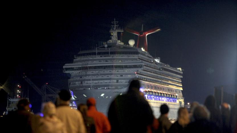 The Carnival Triumph cruise ship is towed towards the dock as spectators watch at the port of Mobile, Alabama, February 14, 2013. The 893-foot (272 meter) vessel, notorious for reports of raw sewage from overflowing toilets, has been without propulsion and running on emergency generator power since Sunday, when an engine room fire left it adrift in the Gulf of Mexico.  REUTERS/ Lyle Ratliff  (UNITED STATES - Tags: SOCIETY HEALTH TRAVEL MARITIME TRANSPORT BUSINESS)