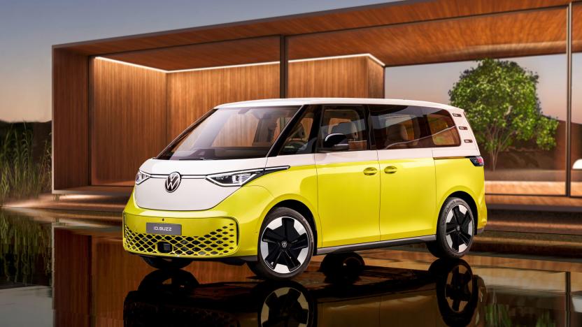 The Volkswagen ID.Buzz EV van in yellow and white pictured on a shiny black floor with a minimal modern wooden structure in the background.