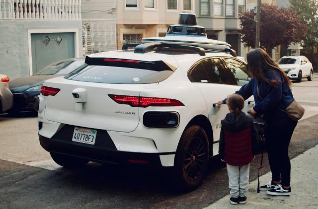 A woman and child stepping into an autonomous Waymo car