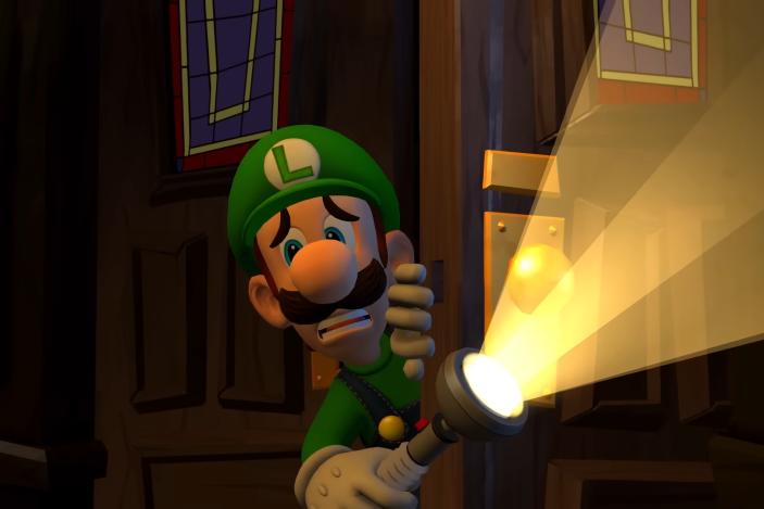 Still from the Luigi's Mansion 2 HD remake trailer. View from inside a dark room of Luigi entering through double doors, looking scared and holding a flashlight.