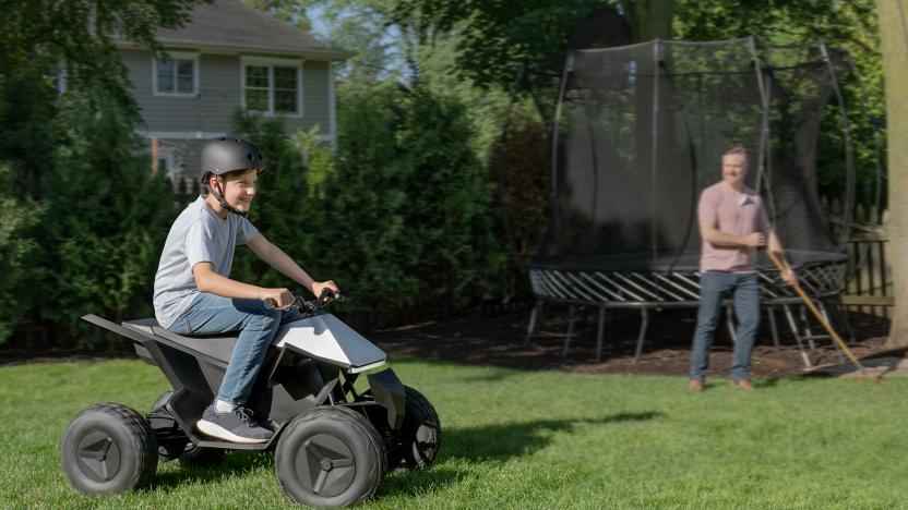 Lifestyle marketing photo of a boy riding an ATV that resembles the Tesla Cybertruck. A proud father beams from behind as he rakes leaves.