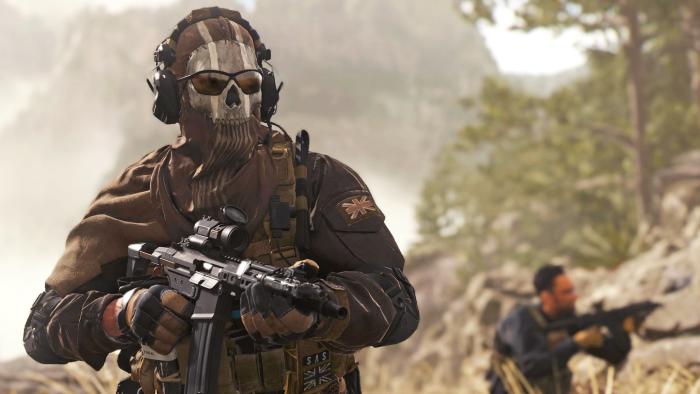 A still image from 'Call of Duty: Modern Warfare 2' showing two soldiers in tall grass. One wears a skull mask and sunglasses as he heads toward the camera with a gun raised.