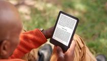 A bald man reading a Kindle.