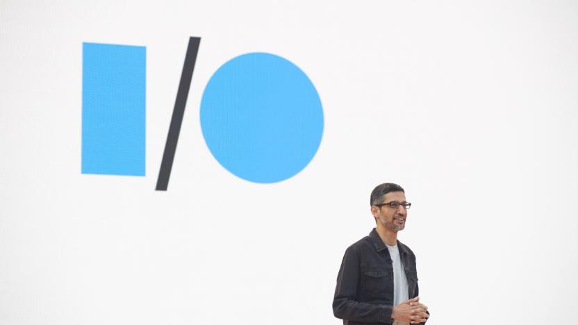 Sundar Pichai, Google's CEO, stands in front of a blank white screen with the blue and black Google I/O logo.