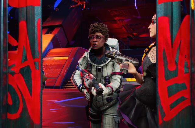 Gameplay still from the canceled multiplayer shooter ‘Hyenas.’ A person in a spacesuit with a gun walks toward sliding doors with another (armed) person guarding the door with a pleased look. Futuristic indoor space setting.