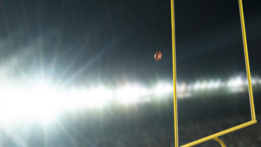 Making a field goal or extra point through the goal post during an American football game at night in stadium with lens flare from the lights.