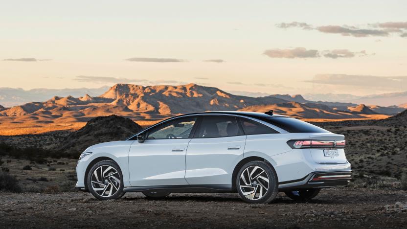 A white Volkswagen ID.7 is parked sideways at the edge of a desert and canyon landscape at dusk.