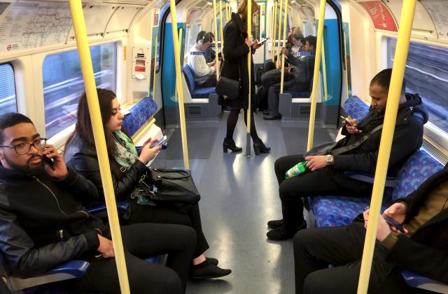 Commuters use their mobile devices on an underground tube train in London April 8, 2015.     REUTERS/Russell Boyce